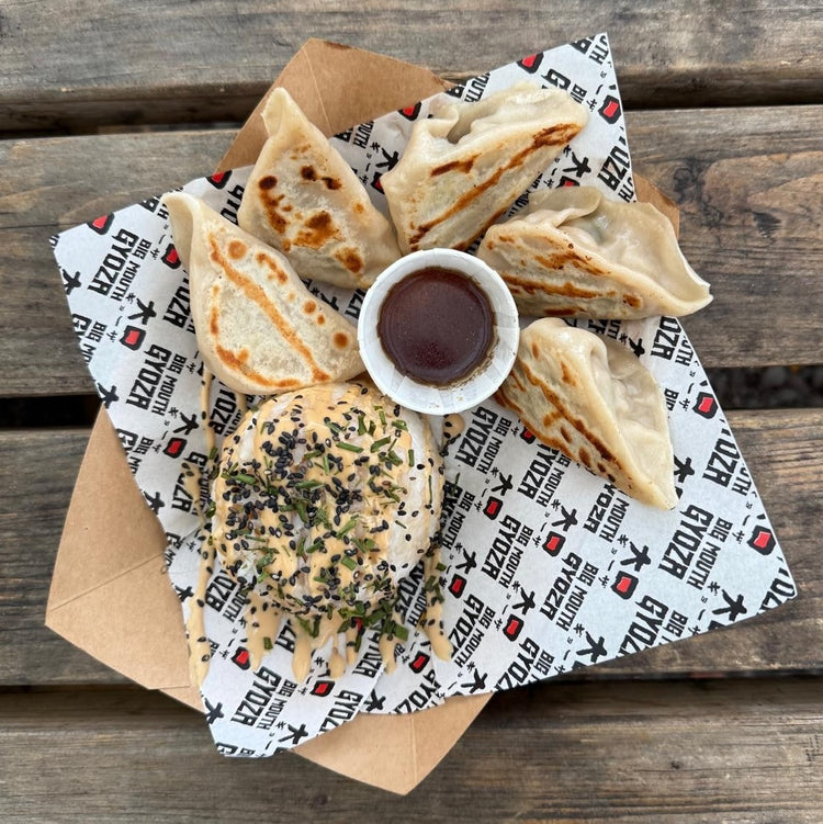 Gyoza and a rice mound with dipping sauce on an outdoor picnic table